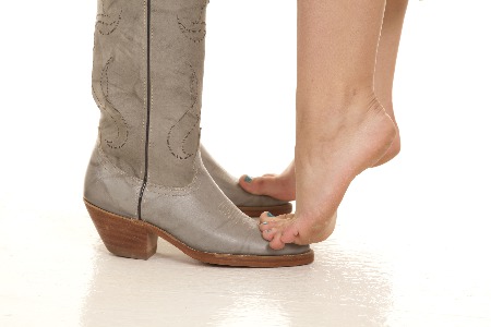 Bare female feet on tip-toe standing on cowboy boots
